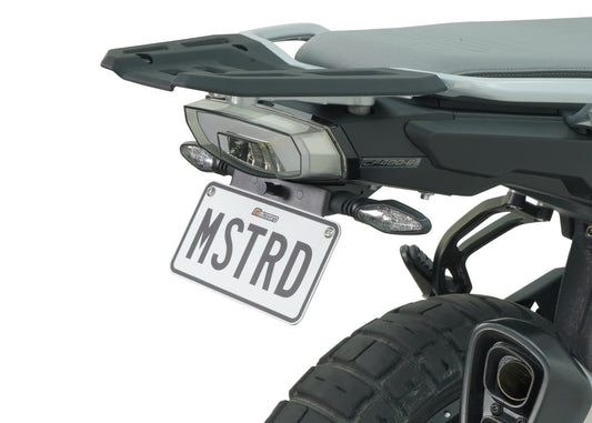 A motorcycle fender eliminator kit, featuring a black aluminum license plate holder with an LED light, mounted on the rear of a motorcycle.