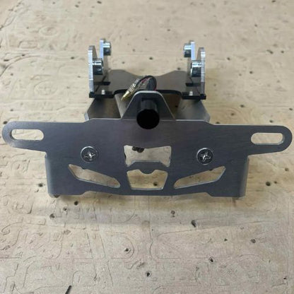 Close up of an aluminium yamaha R9 tail tidy, with all components mounted together on a wooden backdrop.